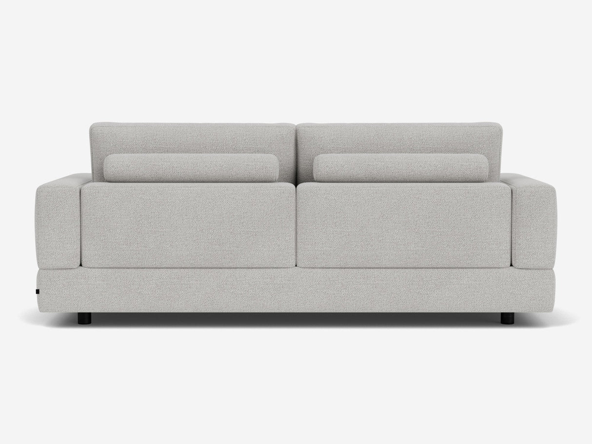 The Stage Track Sofa features a modern, light gray design with a minimalist aesthetic. It has a rectangular shape, two attached back cushions, and short black legs. The upholstery is soft and textured, making it an excellent addition to any contemporary living space.
