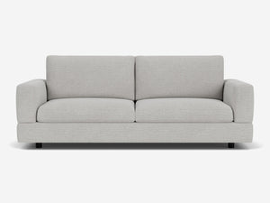 The Stage Track Sofa is a modern two-seater in light gray, featuring plush cushions and a minimalist design. It boasts square arms and a low-profile base, set against a plain white background.
